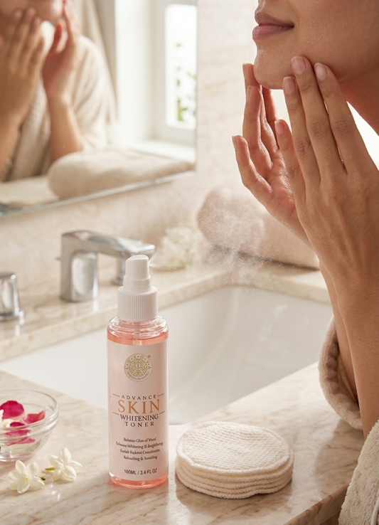 Person applying toner to face with a bottle of toner on a bathroom counter.